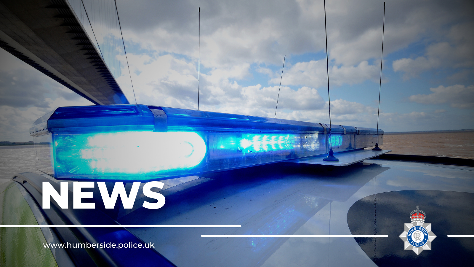 Close up of police lights on top of police car flashing blue in front of the Humber Bridge