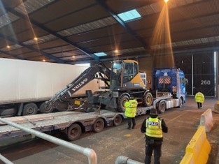 Photo showing lorry with building machinery on its trailer